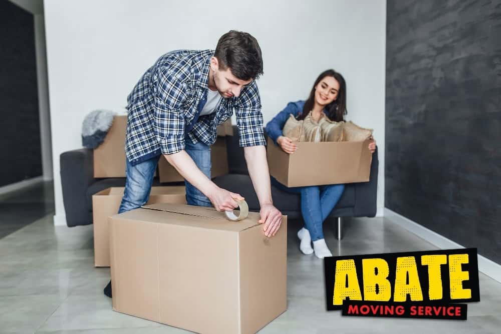 Happy young couple packing cardboard boxes during relocation