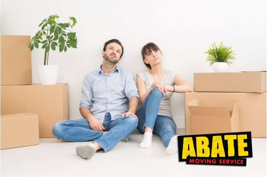 Couple sitting on floor surrounded by moving boxes while preparing for home relocation